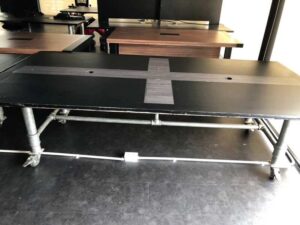 Work desk, 4 seats, steel frame, wooden top, black, with wheels.