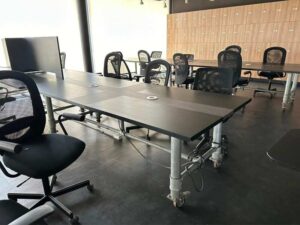 Work desk, 4 seats, steel frame, wooden top, black, with wheels.