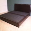 6 foot bed, wooden frame, brown leather covering.