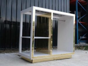 1 product shelf, 2 hanging rails, glass top, white wooden frame with shiny gold trim.