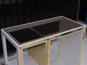 1 product shelf, 2 hanging rails, glass top, white wooden frame with shiny gold trim.