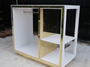 1 product shelf, 2 hanging rails, glass top, white wooden frame with shiny gold trim.