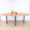 Conference table, steel legs, wooden top, oval shape.