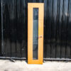 Tall, narrow wooden door with clear glass panels and lever-type knobs.