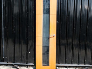 Tall, narrow wooden door with clear glass panels and lever-type knobs.