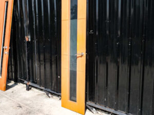 Tall, narrow wooden door with clear glass panels and lever-type knobs.