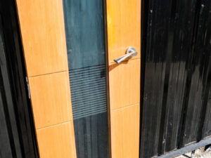 Tall, narrow wooden door with clear glass panels and lever-type knobs.