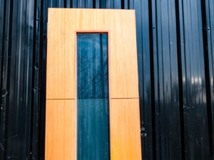 Tall, narrow wooden door with clear glass panels and lever-type knobs.