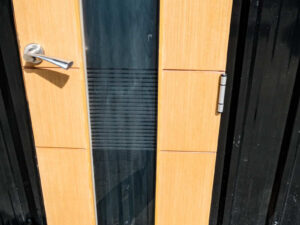 Tall, narrow wooden door with clear glass panels and lever-type knobs.