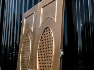 Double wooden doors, round mullions, twist latch, gold color.
