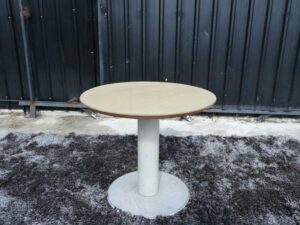 Round table, white steel legs, wooden top, light cream/beech wood color.
