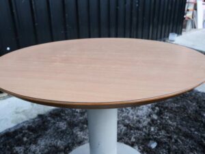 Round table, white steel legs, wooden top, light cream/beech wood color.