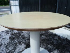 Round table, white steel legs, wooden top, light cream/beech wood color.