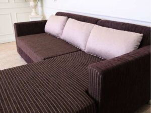 L sofa with pillows, fabric cushions, wooden frame, steel legs, brown.