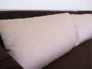 L sofa with pillows, fabric cushions, wooden frame, steel legs, brown.