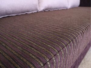L sofa with pillows, fabric cushions, wooden frame, steel legs, brown.
