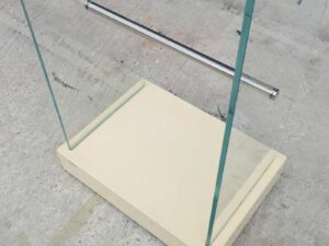 Product hanging rack Product hanging shelf, glass walls on 2 sides, 3 hanging rails, cream colored wooden base.