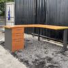 L-shaped work desk with drawers, steel legs, wooden top.