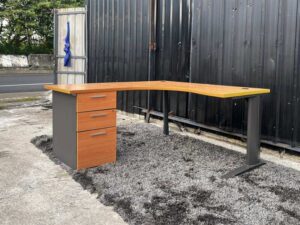 L-shaped work desk with drawers, steel legs, wooden top.
