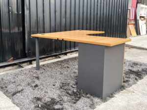 L-shaped work desk with drawers, steel legs, wooden top.