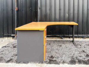 L-shaped work desk with drawers, steel legs, wooden top.