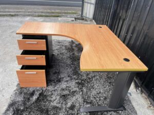 L-shaped work desk with drawers, steel legs, wooden top.