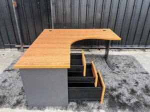 L-shaped work desk with drawers, steel legs, wooden top.