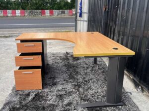 L-shaped work desk with drawers, steel legs, wooden top.