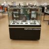 Jewelry cabinet, glass product display cabinet with 4 opening doors, black wood frame, with LED lights along the glass edges.