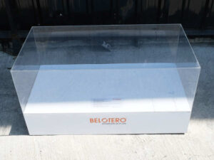 Clear acrylic product display shelf, white wooden frame, wide horizontal.