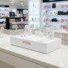 Clear acrylic product display shelf, white wooden frame, wide horizontal.