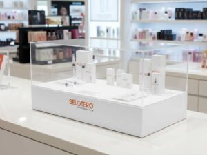 Clear acrylic product display shelf, white wooden frame, wide horizontal.