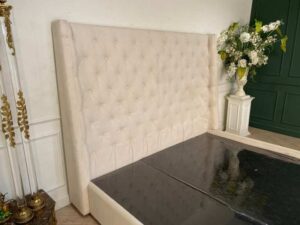 Bed 6 feet, wooden frame, fabric covered, cream color.