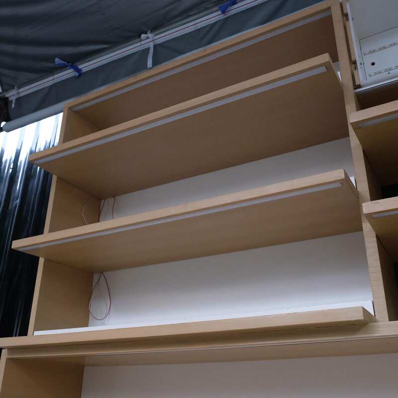 Product shelves, 2 sides, brown wooden frame. The bottom has 4 storage drawers on each side.