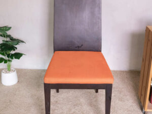 Wooden chair, orange fabric cushion, beautiful frame, slightly curved backrest.