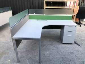 L-shaped corner desk with light gray filing cabinet and partition.