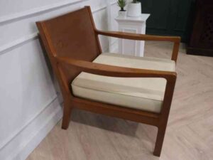 Chair with armrests, wooden frame. Seat cushion made of fabric.