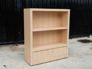 Product shelf, 2-level shelves, 2 storage cabinets with open doors, light brown wooden frame.