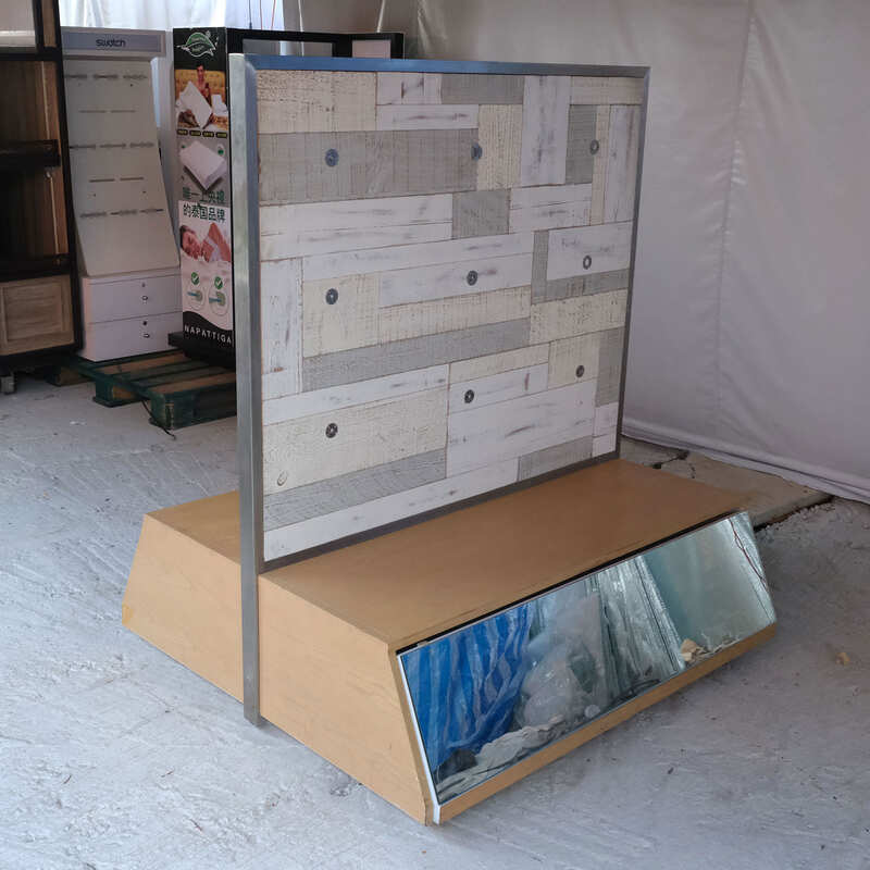 Product shelves, display stands, 2 sides, brown wooden base. Has a drawer in front of a mirror and has wheels
