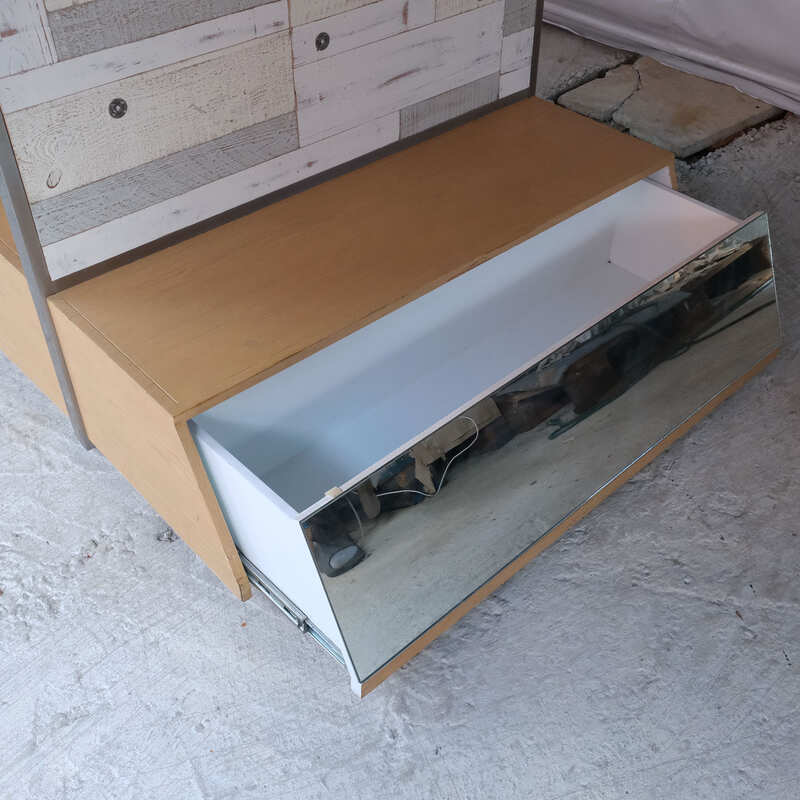 Product shelves, display stands, 2 sides, brown wooden base. Has a drawer in front of a mirror and has wheels