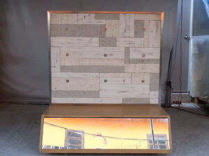 Product shelves, display stands, 2 sides, brown wooden base. Has a drawer in front of a mirror and has wheels