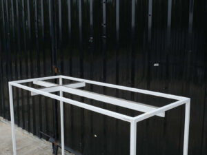 Open product shelves, with a hanging rail at the top. white steel frame Brown wood pattern base