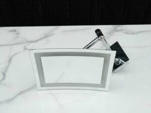 Shaving mirror in the bathroom, wall mounted, has built-in lights, steel cantilever legs.