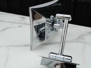 Shaving mirror in the bathroom, wall mounted, has built-in lights, steel cantilever legs.