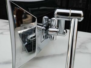 Shaving mirror in the bathroom, wall mounted, has built-in lights, steel cantilever legs.