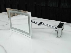 Shaving mirror in the bathroom, wall mounted, has built-in lights, steel cantilever legs.