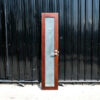 Tall, narrow wooden door, glass panel, lever-type knob.