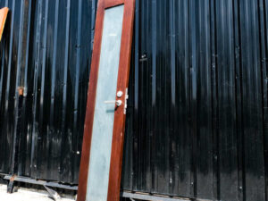 Tall, narrow wooden door, glass panel, lever-type knob.