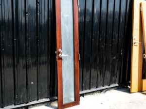 Tall, narrow wooden door, glass panel, lever-type knob.