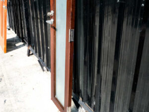 Tall, narrow wooden door, glass panel, lever-type knob.